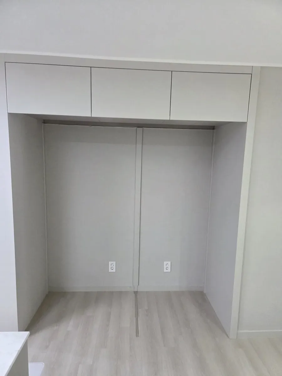 뒷벽 하단에 콘센트 두 개가 있는 빈 냉장고 칸과 상부장 세 칸